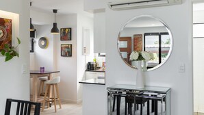 Una cocina moderna con un espejo redondo, paredes blancas y un comedor con mesa negra y sillas blancas.
