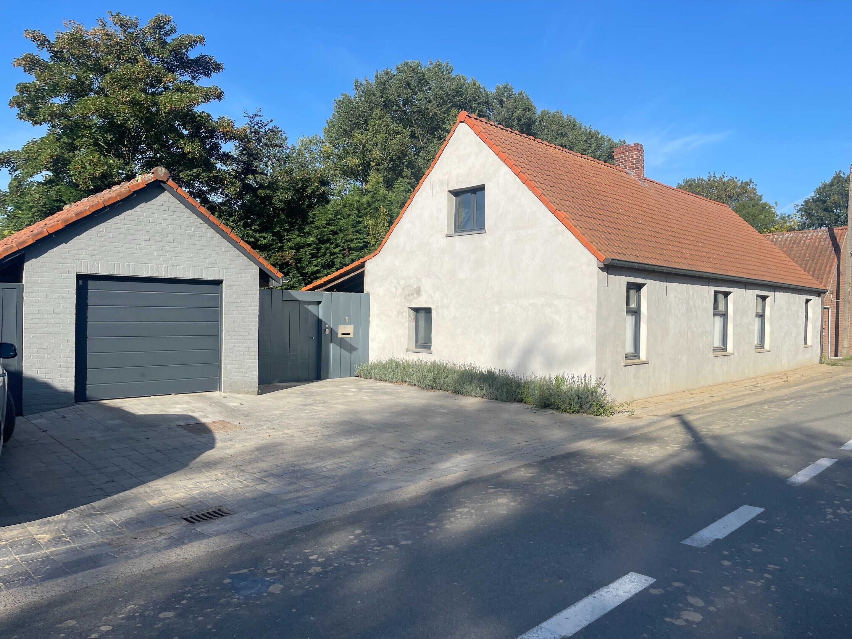 A two-story building with a garage, a small window, and a red-tiled roof.