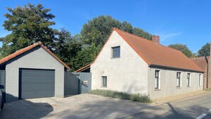A two-story building with a garage, a small window, and a red-tiled roof. - Holiday Home With Pool and Large Garden (Zwevegem)