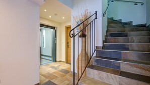 A staircase with a metal handrail and a vase of dried plants. - Brunner Apartment Near the Markbachjoch Cable car (Wildschönau)