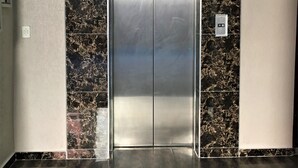 An elevator with a digital display showing the number 6, surrounded by marble walls and a tiled floor. - PLM Palace Lodge (Durban)
