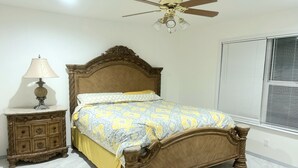 A bedroom with a wooden bed, a nightstand, a lamp, a ceiling fan, and a window with blinds. - Built in 2025 - In the heart of Lubbock (Lubbock)