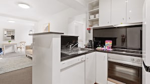 A modern kitchen with white cabinetry, a Bosch dishwasher, a black stove, and a built-in oven. - Chic 1-bed Apartment Steps From Shopping Street (Melbourne)