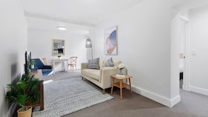 A modern living room with a sofa, coffee table, and decorative items. - Chic 1-bed Apartment Steps From Shopping Street (Melbourne)