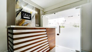Un mostrador de recepción con pared de mármol y señalización de servicios ofrecidos por la empresa.