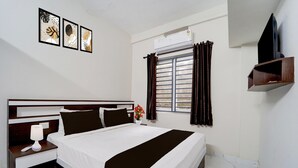 Habitación de hotel con cama, mesita de noche, lámpara y ventana con cortinas.