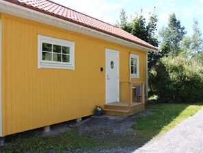 A yellow building with a red roof, a white door, and a small porch with steps. - 4 Person Holiday Home in Lur (Lur)