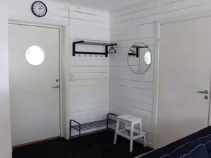 A room with a white door, a small white stool, a black metal shelf, and a round mirror on the wall. - 4 Person Holiday Home in Lur (Lur)