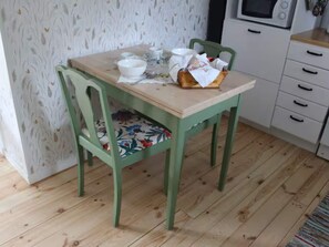 A dining table with chairs, a microwave, and a cabinet in a room with patterned wallpaper. - 4 Person Holiday Home in Lur (Lur)