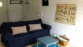 A cozy living room with a dark blue sofa, a small grey side table, and a blue rug.