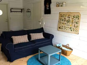 Un salon chaleureux avec un canapé bleu foncé, une petite table d’appoint grise et un tapis bleu.