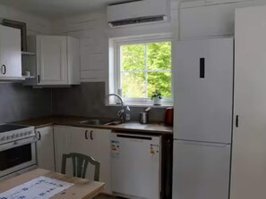 A kitchen with white cabinets, a window, a sink, a stove, and a refrigerator. - 4 Person Holiday Home in Lur (Lur)