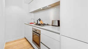 Een moderne keuken met witte kasten, een roestvrijstalen oven en een gasfornuis.