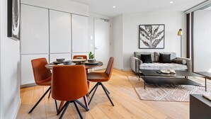 Een moderne woonkamer met een bank, salontafel en een eethoek met stoelen en een tafel.