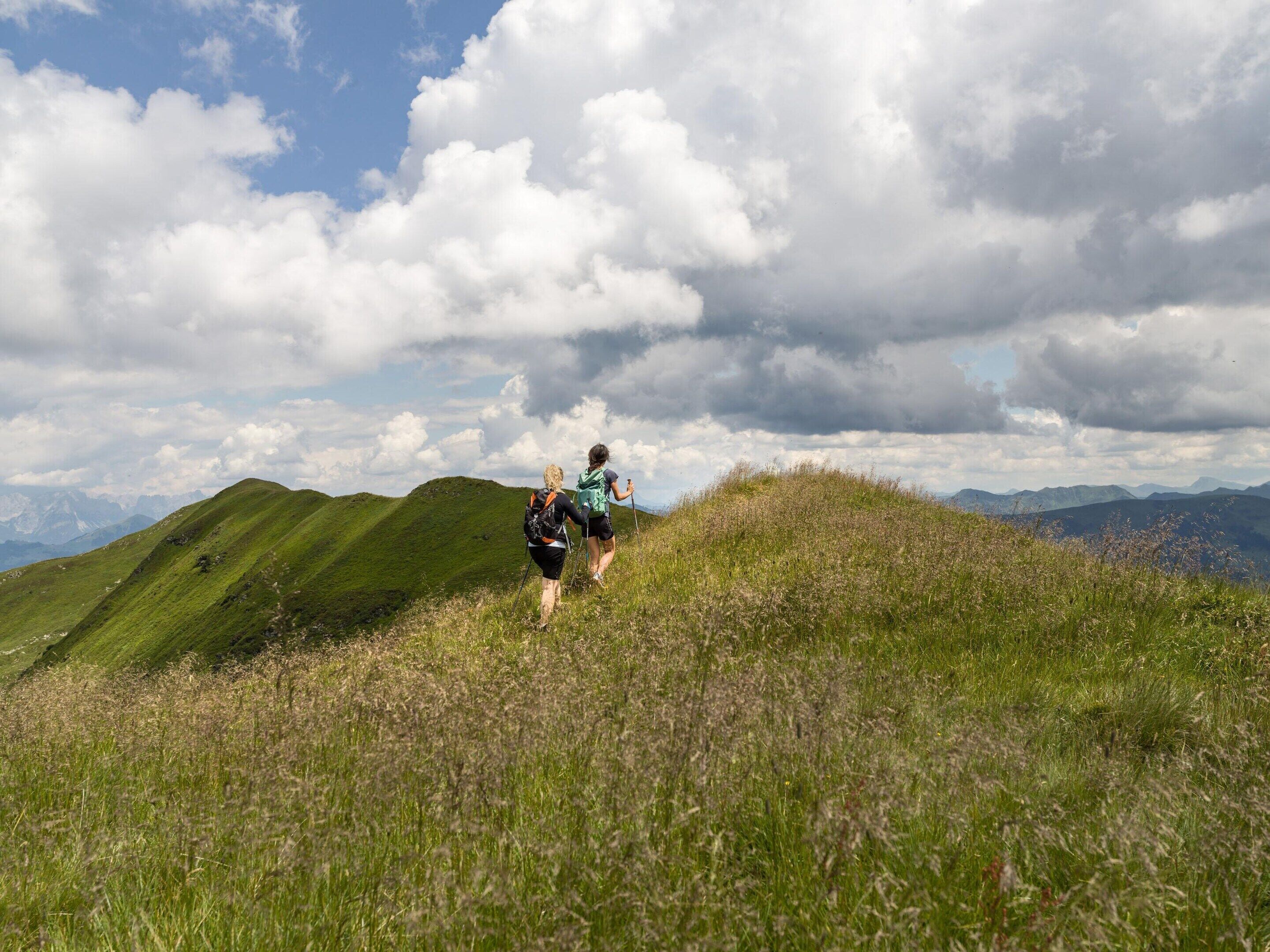A hilly landscape with two hikers.