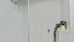 A modern shower area with a glass door, a small potted plant, and a textured wall. - Fitzroy North 1-bed With Balcony by Edinburgh Park (Melbourne)