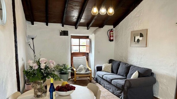 A cozy living room with a grey sofa, a dining table with chairs, and a vase of flowers. - Sofia House With Pool in Granadilla de Abona (Granadilla de Abona)