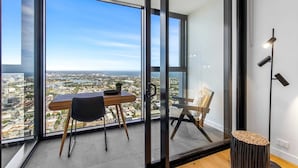 A modern room with a large glass window, a wooden table, two chairs, and a small stool. - Modern 1-bed in Hip Southbank With Pool & Gym (Melbourne)
