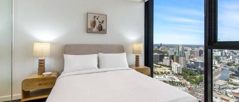 Una camera d'albergo moderna con un letto grande, due comodini con lampade, vista sulla città e un quadro appeso al muro.
