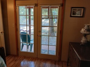 A room with a wooden floor, a green chair, and a door leading outside. -  Magical 1 bd cabin-a soothing Mokelumne Hill getaway: Center of the Universe. (Mokelumne Hill)