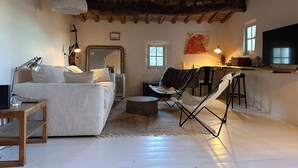 Un accogliente soggiorno con soffitto in legno, un divano, un tavolino da caffè e una televisione.
