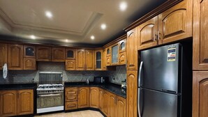 A kitchen with wooden cabinets, a stainless steel refrigerator, and a built-in oven. - فيلا للايجار اليومي خمس غرف مستقله (6 اكتوبر)