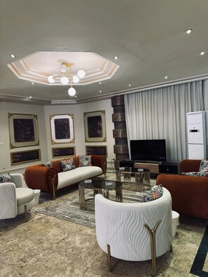 Een moderne woonkamer met een zithoek, een salontafel en een flatscreen televisie.