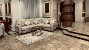 A spacious living room with a beige sectional sofa, a glass coffee table, and a patterned rug. - فيلا للايجار اليومي خمس غرف مستقله (6 اكتوبر)