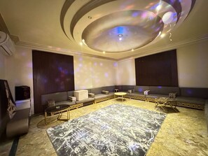 Een moderne lounge met een patroonrijk tapijt, zitopstellingen en een plafond met een lamp.