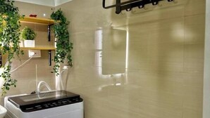 Une salle de bain avec des toilettes blanches, un porte-serviettes noir et un lave-linge blanc.