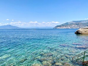 A clear coastal view with rocky terrain and a distant mountain. - Gaiano APT Casette (Sorrento)