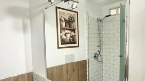 Ein Badezimmer mit Dusche, Waschbecken und einem gerahmten Bild an der Wand.