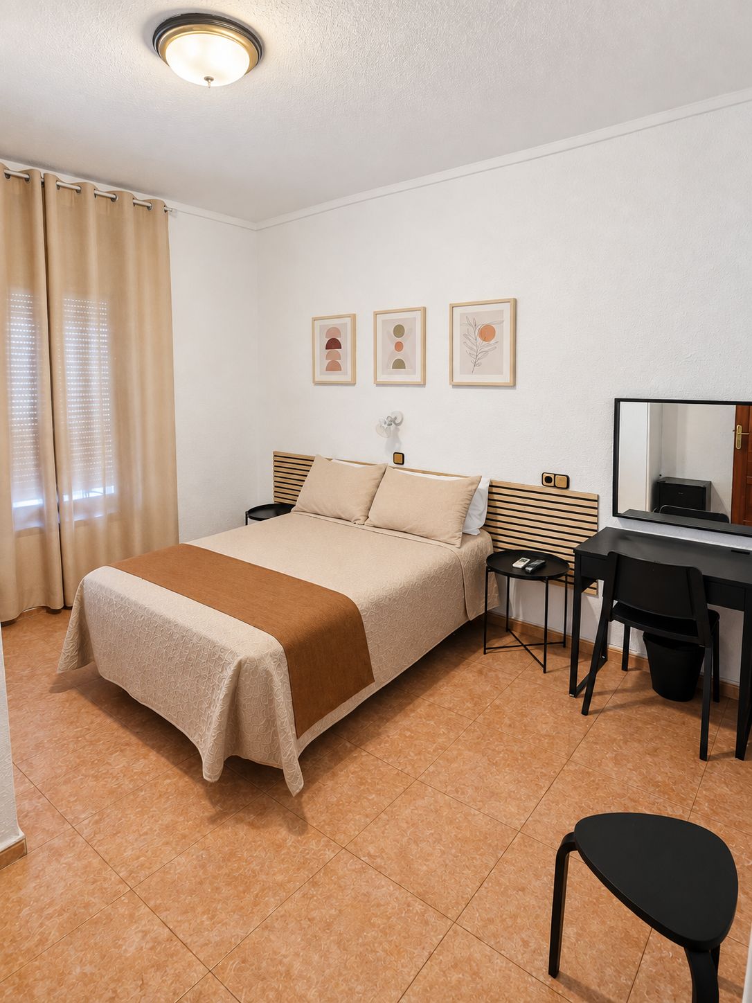 Une chambre d’hôtel avec un lit, un bureau, une chaise, une petite table et un miroir.