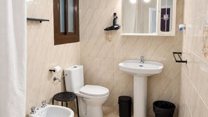 A bathroom with a toilet, bidet, sink, and bathtub. - Hostal Prada (Madrid)