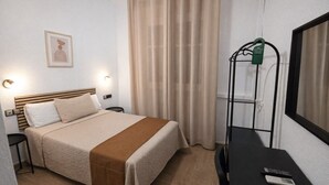 A hotel room with a bed, bedside tables, a desk with a chair, a hanging coat rack, and a window with curtains. - Hostal Prada (Madrid)