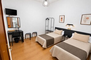 Une chambre d’hôtel avec deux lits, un bureau, une chaise, une télévision et un miroir.