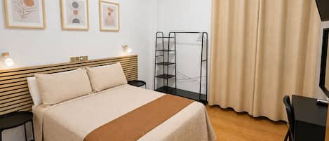 A neatly arranged bedroom with a bed, bedside tables, a wall-mounted air conditioner, a shelf unit, and a curtain.
