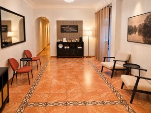 A hotel lobby with a reception desk, seating area, and a patterned floor. - Hostal Prada (Madrid)