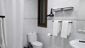 A modern bathroom with a toilet, bidet, sink, and a small stool. - Hostal Prada (Madrid)