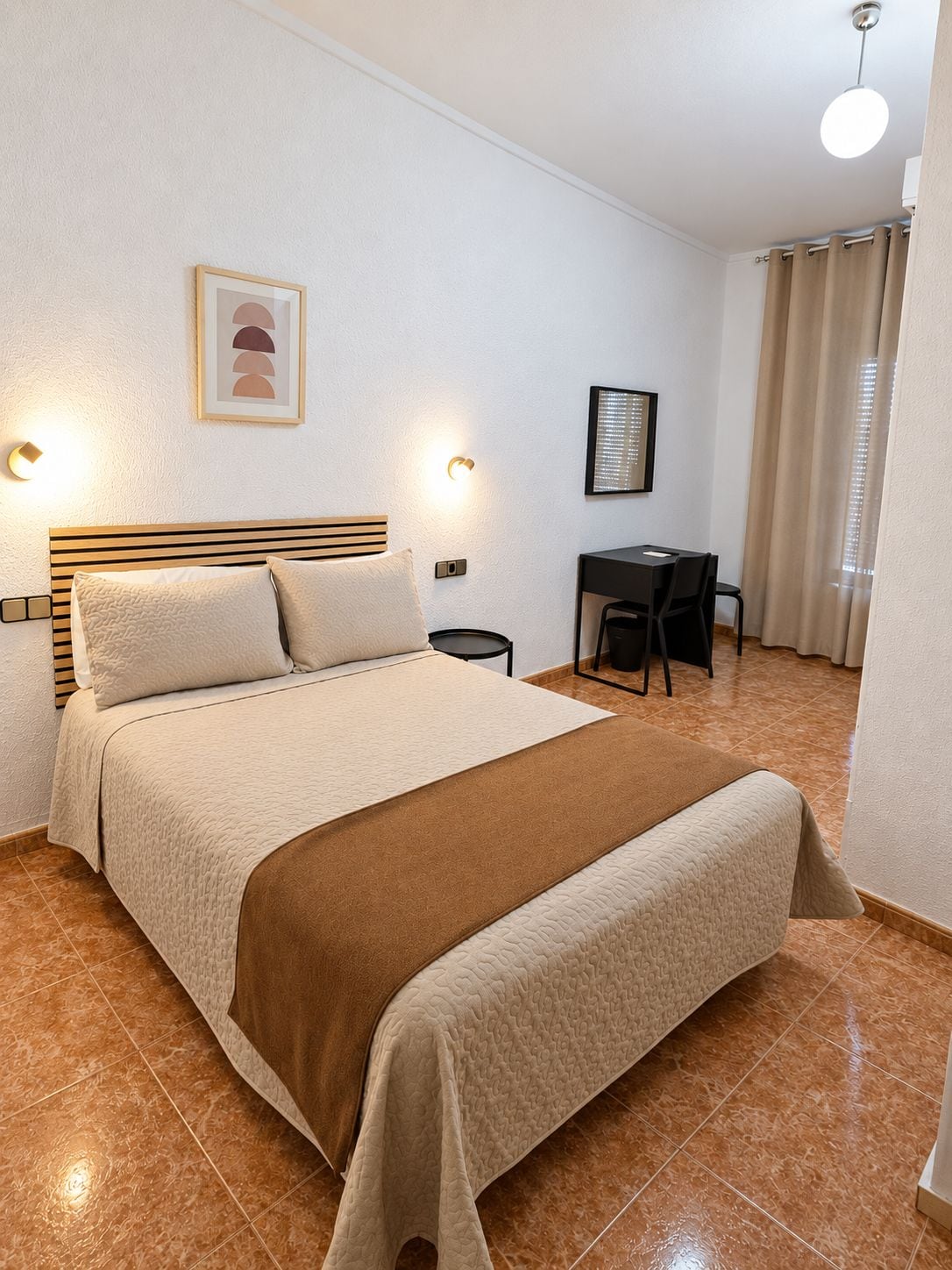 Una habitación de hotel con una cama, lámparas de noche, un escritorio y una silla.