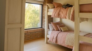 Dormitorio con literas, ventana, vigas de madera y pared de ladrillo.