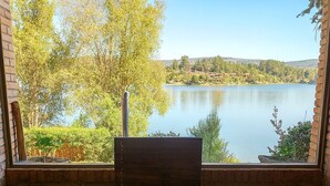 Una habitación con vistas a un lago, un banco de madera y un tapete verde.