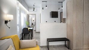A modern living room with a sofa, a coffee table, a dining area with chairs, a black bench, and a wardrobe. - Athens Praxitelous Vibes (Athina)