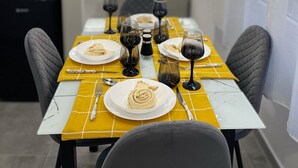 A dining area with a yellow tablecloth, plates, wine glasses, and cutlery. - Athens Praxitelous Vibes (Athina)