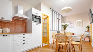 Una cocina moderna con armarios blancos, horno integrado y un salpicadero con motivo de espiga.