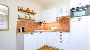 Una cocina moderna con armarios blancos, encimeras de madera, horno integrado y un salpicadero con motivo de espiga.