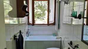 Un bagno compatto con vasca, water e lavandino.