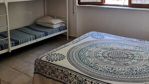 Una camera del dormitorio con letti a castello, una finestra con tende e una coperta a motivi.