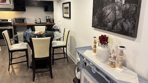 Una cucina moderna con zona pranzo, caratterizzata da un tavolo in vetro, sedie e un vaso decorativo su un tavolo consolle.