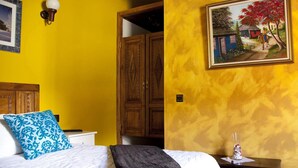 Une chambre à coucher comprenant un lit, une table de chevet, une armoire en bois, un luminaire fixé au mur et un tableau encadré.